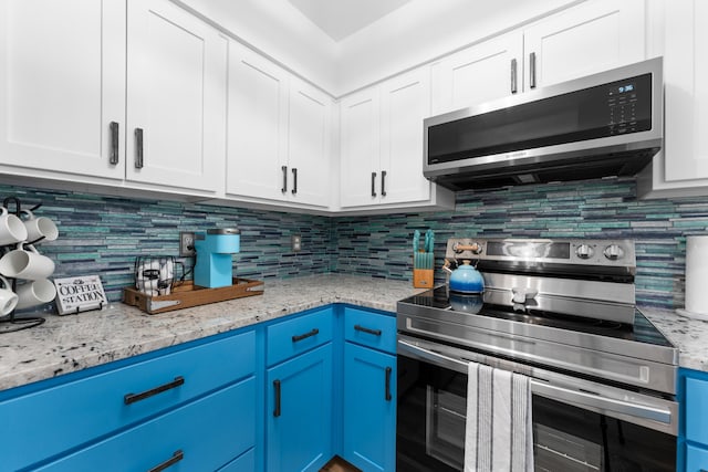 kitchen with blue cabinetry, white cabinets, appliances with stainless steel finishes, and backsplash