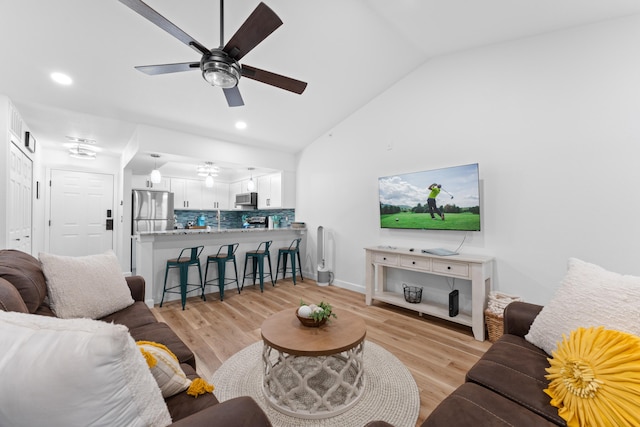 living room featuring ceiling fan, lofted ceiling, and light hardwood / wood-style flooring