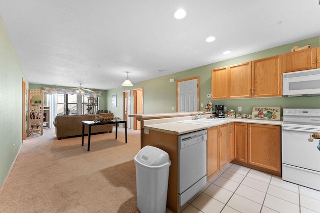 kitchen featuring hanging light fixtures, sink, kitchen peninsula, white appliances, and light carpet