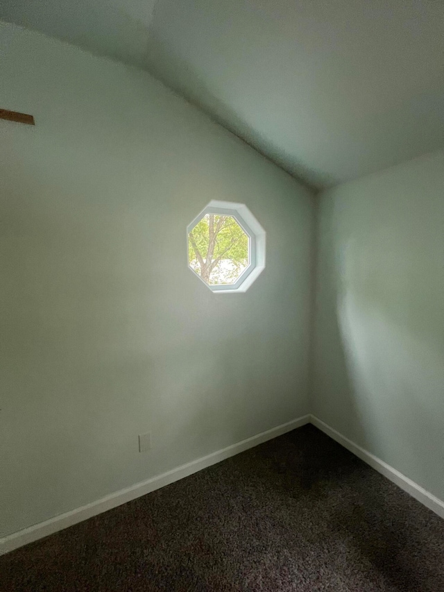 carpeted spare room featuring vaulted ceiling