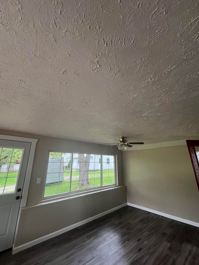 unfurnished room with ceiling fan, a healthy amount of sunlight, dark hardwood / wood-style flooring, and a textured ceiling