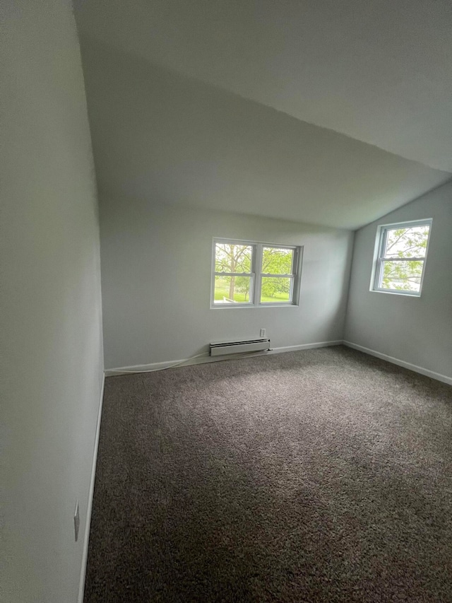 carpeted spare room featuring vaulted ceiling and a baseboard heating unit