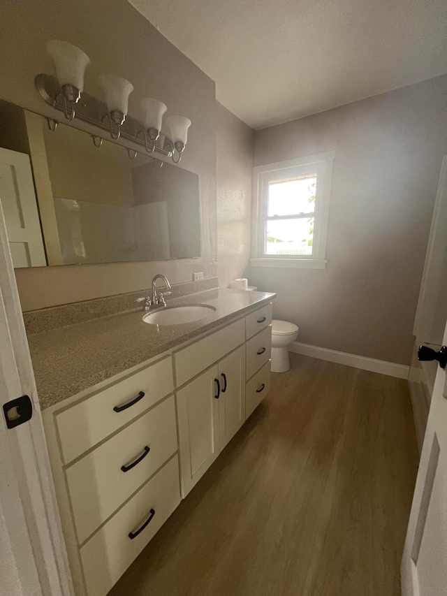 bathroom featuring wood-type flooring, vanity, and toilet