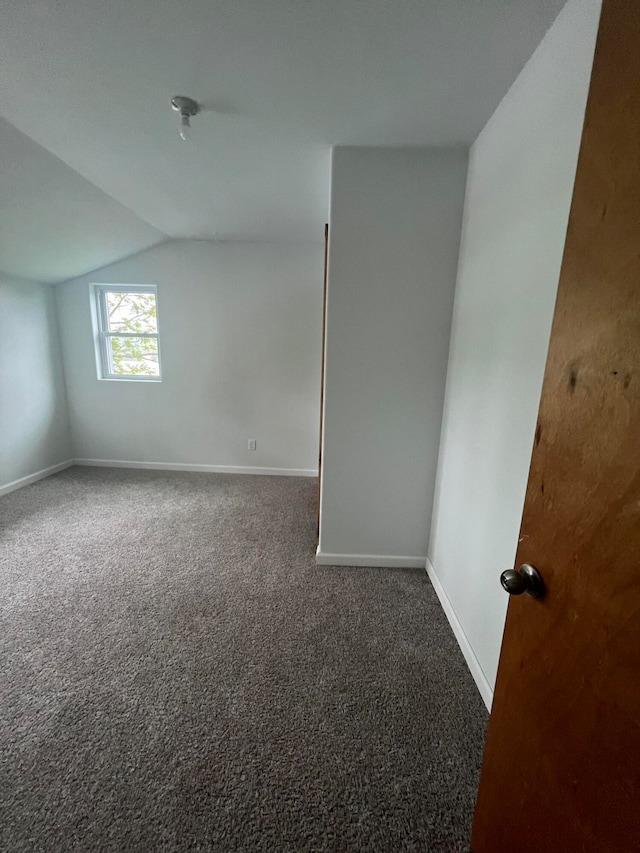 carpeted spare room with lofted ceiling