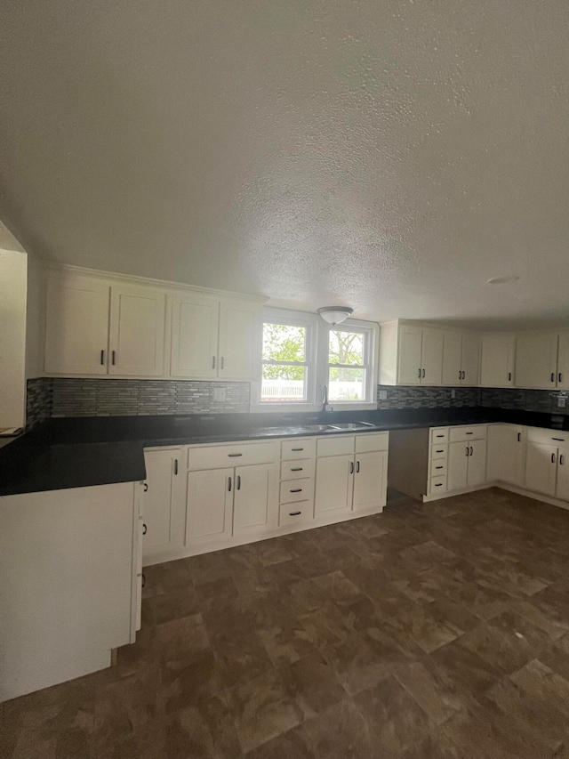 kitchen with tasteful backsplash, white cabinets, and a textured ceiling