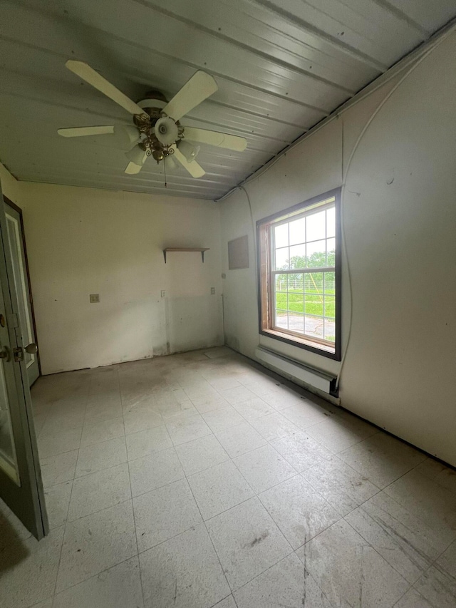 unfurnished room featuring ceiling fan and a baseboard heating unit