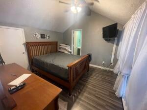 bedroom with ceiling fan, lofted ceiling, and dark wood-type flooring