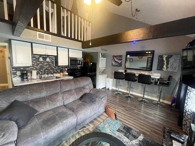 living room featuring a high ceiling, ceiling fan, sink, and dark hardwood / wood-style floors