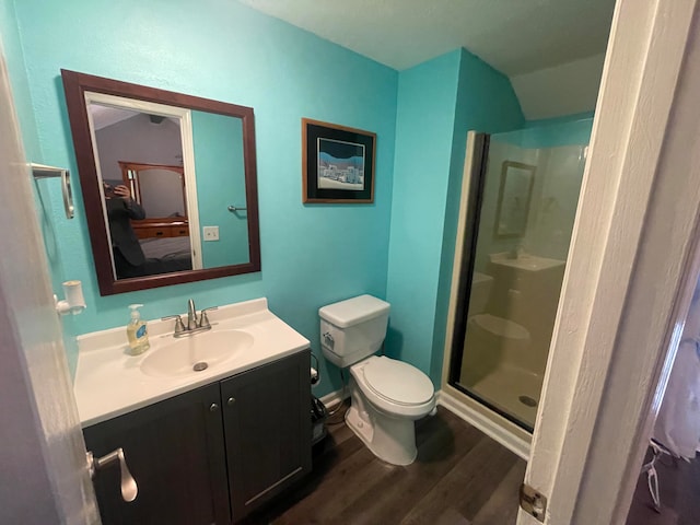 bathroom with wood-type flooring, a shower with shower door, vanity, and toilet