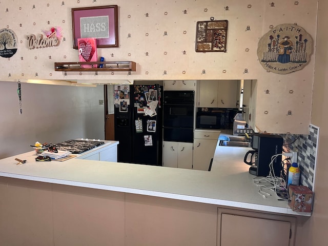 kitchen with sink, kitchen peninsula, and black appliances