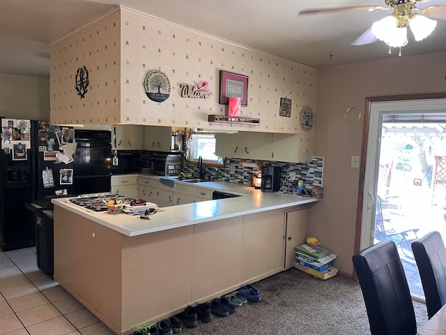 kitchen featuring kitchen peninsula, stainless steel gas cooktop, sink, and black refrigerator with ice dispenser