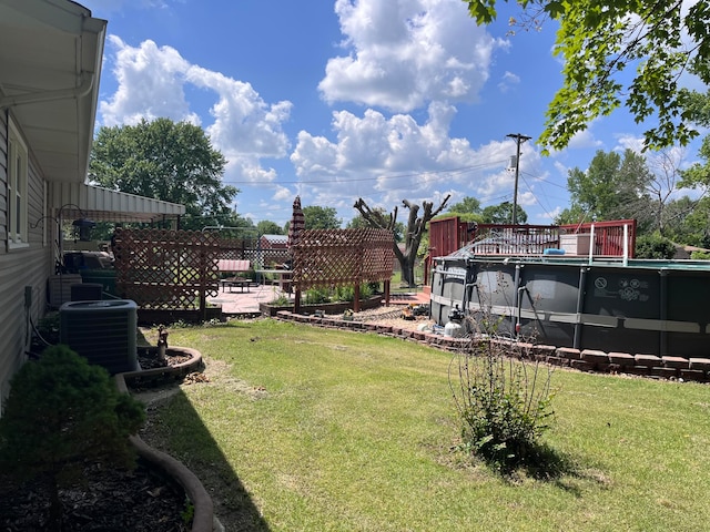 view of yard featuring a pool side deck and central AC unit