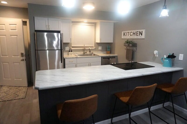 kitchen featuring sink, dark hardwood / wood-style flooring, kitchen peninsula, white cabinetry, and appliances with stainless steel finishes