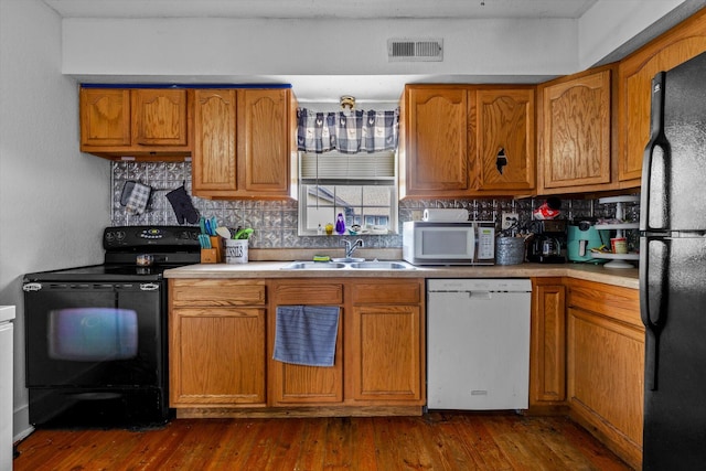 kitchen featuring backsplash, dark hardwood / wood-style floors, black appliances, and sink