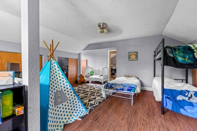 bedroom with ceiling fan, a closet, vaulted ceiling, hardwood / wood-style flooring, and a textured ceiling