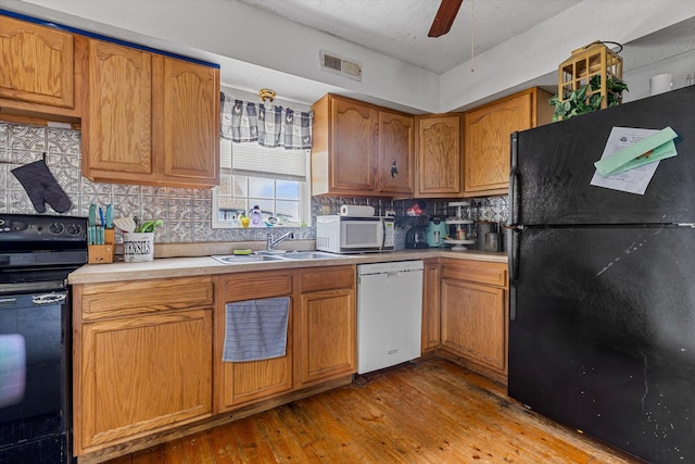 kitchen with backsplash, black appliances, sink, and light wood-type flooring