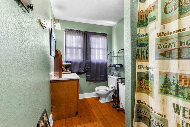 bathroom featuring vanity, a textured ceiling, hardwood / wood-style flooring, a shower with curtain, and toilet