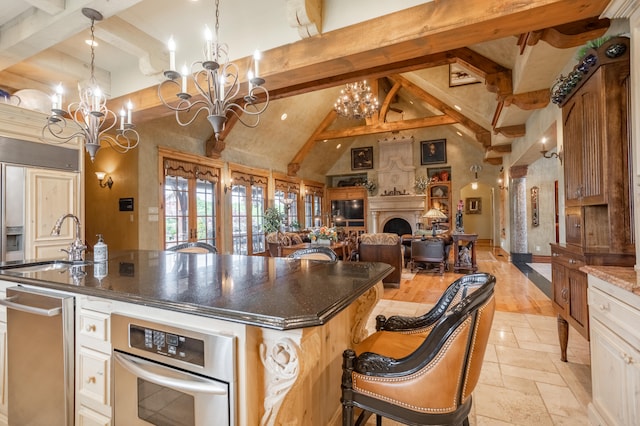 kitchen with pendant lighting, an island with sink, beam ceiling, sink, and light hardwood / wood-style floors