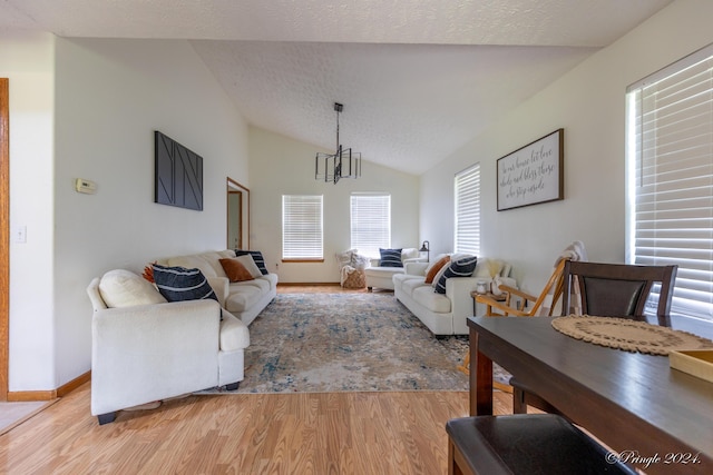 living area with light wood-style flooring, a textured ceiling, lofted ceiling, and an inviting chandelier