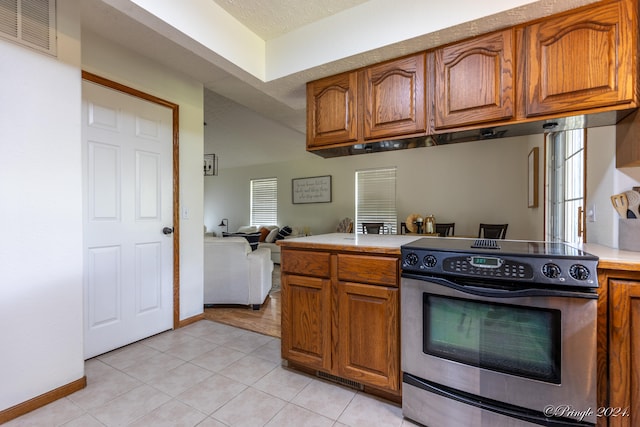 kitchen with a textured ceiling, light tile patterned floors, and electric range