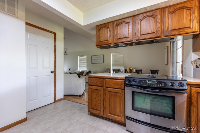 kitchen featuring light countertops, visible vents, light tile patterned floors, stainless steel electric range, and brown cabinetry