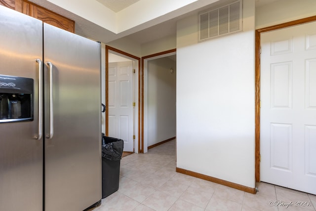 kitchen with stainless steel refrigerator with ice dispenser, light tile patterned flooring, visible vents, and baseboards