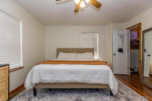 bedroom featuring ceiling fan, dark wood-type flooring, a closet, and a textured ceiling