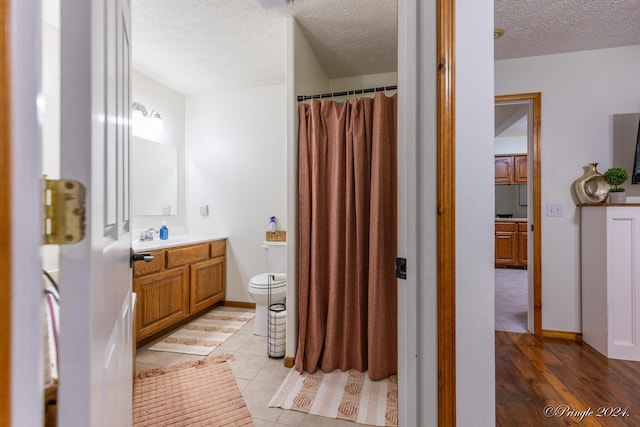 full bathroom featuring a textured ceiling, toilet, vanity, and a shower with curtain