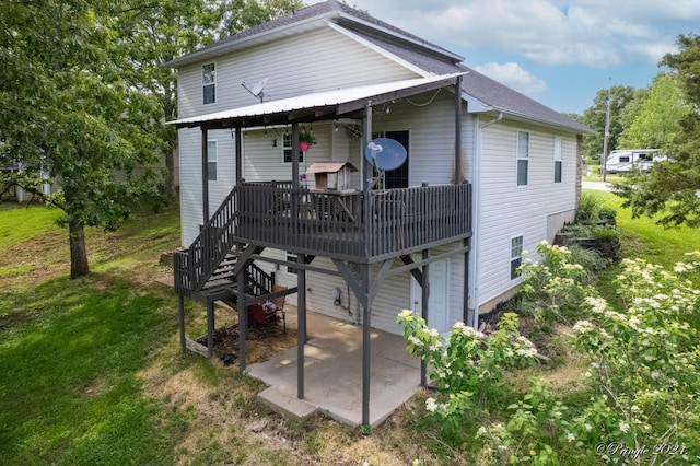 back of property with a yard, a wooden deck, and a patio