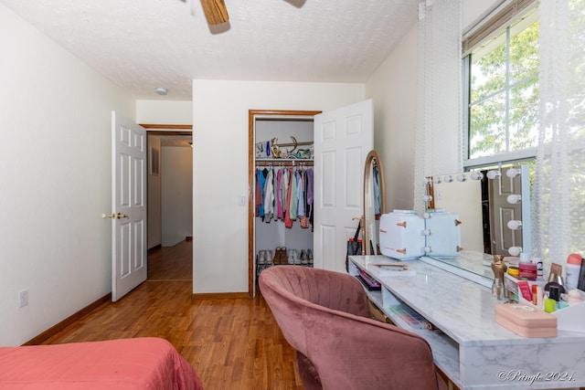 bedroom with a textured ceiling, baseboards, wood finished floors, a closet, and ceiling fan