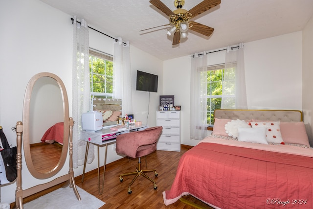 bedroom featuring wood-type flooring, multiple windows, and ceiling fan