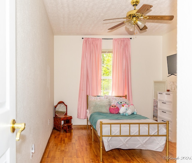 bedroom featuring wood-type flooring, a textured ceiling, and ceiling fan