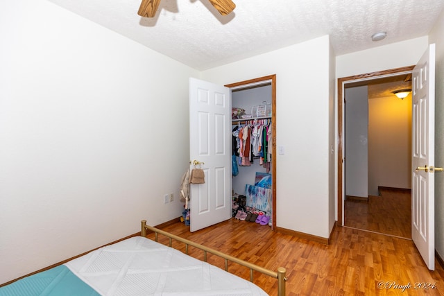 bedroom with a closet, baseboards, light wood-style flooring, a textured ceiling, and ceiling fan