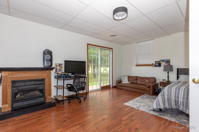 bedroom with a drop ceiling, dark wood-type flooring, and access to outside