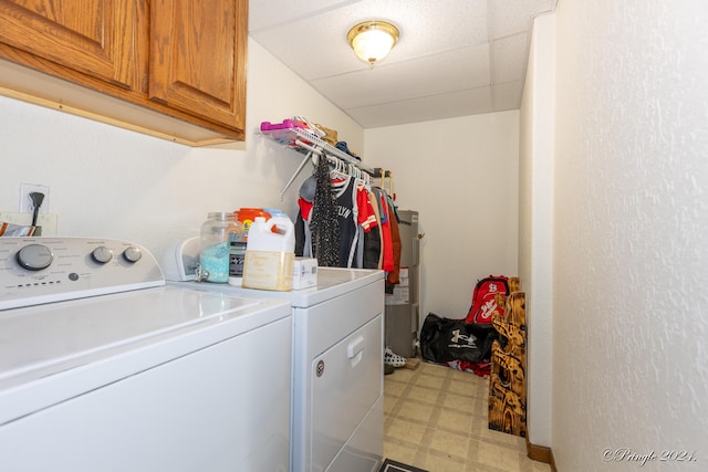 laundry room featuring electric water heater, independent washer and dryer, and cabinets