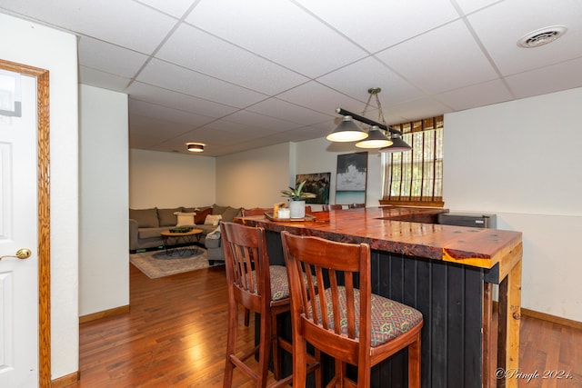 dining area featuring wood-type flooring, a dry bar, visible vents, and a paneled ceiling