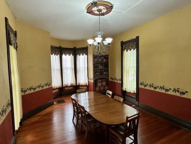 624 S Ash St, Nevada, MO 64772 - dining space featuring baseboards, wood finished floors, and a chandelier