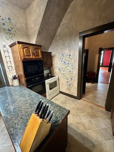 624 S Ash St, Nevada, MO 64772 - kitchen with a peninsula, light tile patterned flooring, dark countertops, baseboards, and black appliances