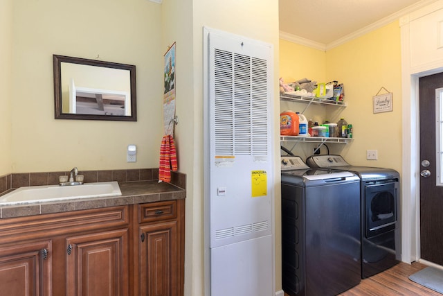 laundry room with separate washer and dryer, hardwood / wood-style flooring, crown molding, and sink