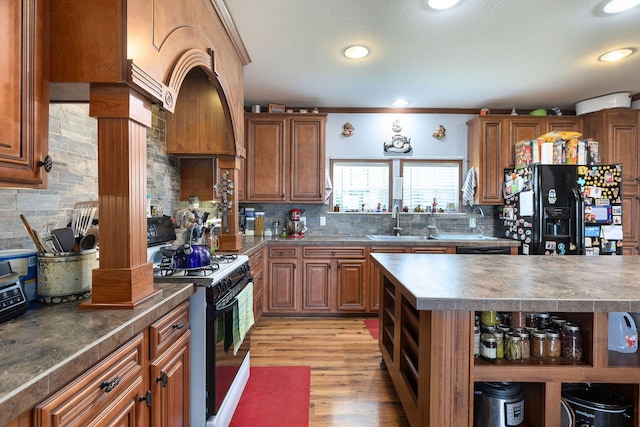 kitchen featuring sink, ornamental molding, backsplash, white gas range, and light wood-type flooring