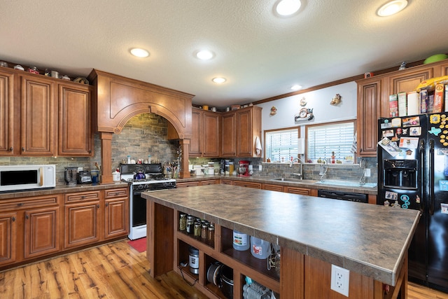 kitchen featuring a kitchen island, light wood-type flooring, white appliances, sink, and crown molding