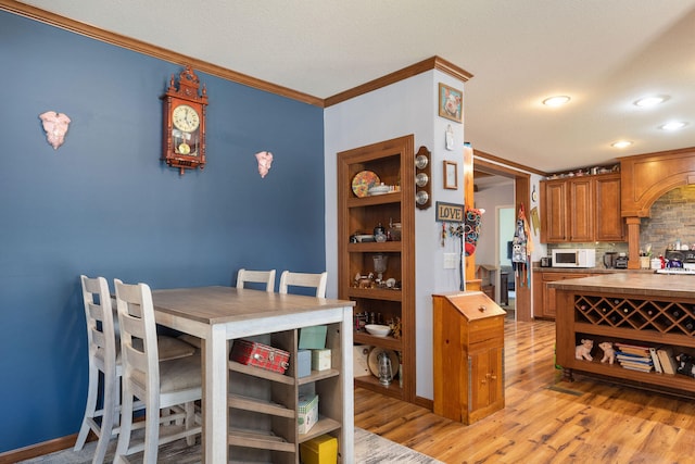 kitchen featuring a kitchen breakfast bar, ornamental molding, light wood-type flooring, and a textured ceiling