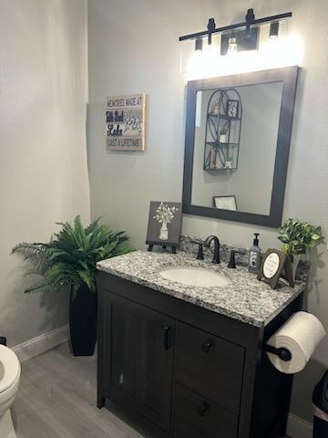 bathroom with toilet, vanity, and hardwood / wood-style flooring