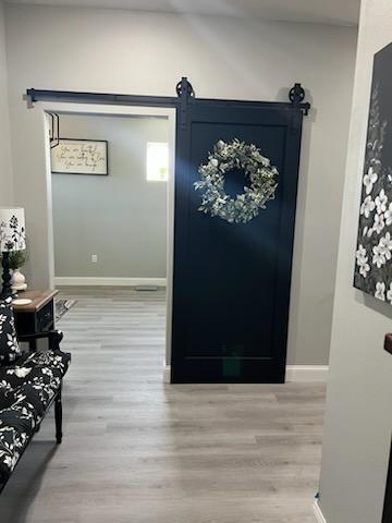 corridor with a barn door and light hardwood / wood-style flooring