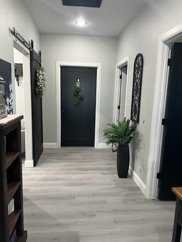 corridor featuring a barn door and light hardwood / wood-style flooring