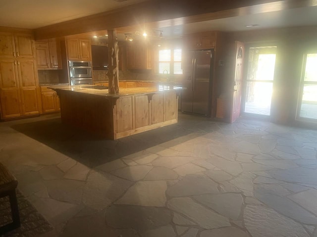 kitchen with double oven, a center island, refrigerator, and a healthy amount of sunlight