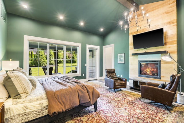 bedroom featuring an inviting chandelier, a towering ceiling, access to exterior, and a large fireplace