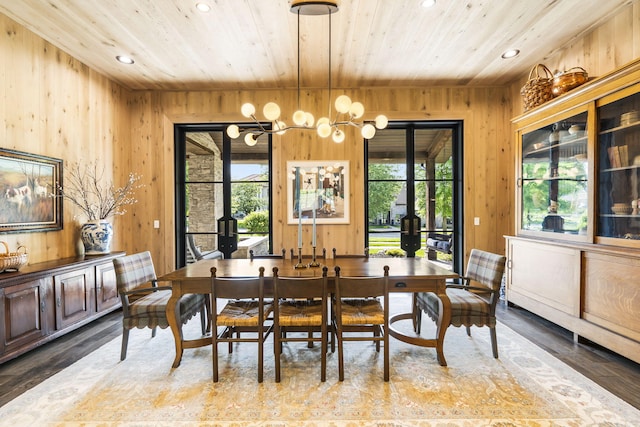 dining room featuring wood-type flooring, wooden walls, a chandelier, and wooden ceiling