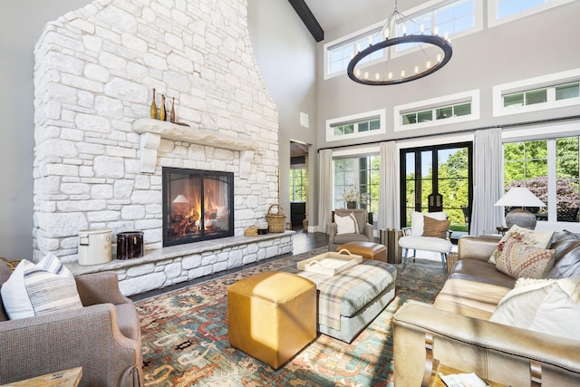 living room with a towering ceiling, a notable chandelier, beamed ceiling, and a fireplace