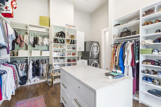 spacious closet with dark hardwood / wood-style floors and stacked washing maching and dryer